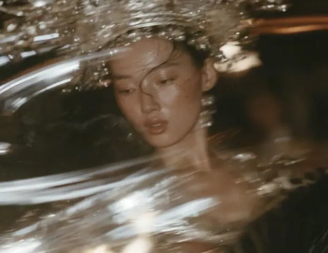 Close portrait of a dancer with lowered eyes, loose dark hair and elaborate silver ornaments