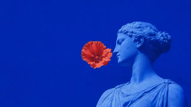 Cobalt blue classical female statue beside a small floating coral red flower