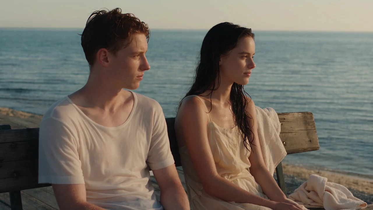 Two people sitting on a seaside bench after a swim
